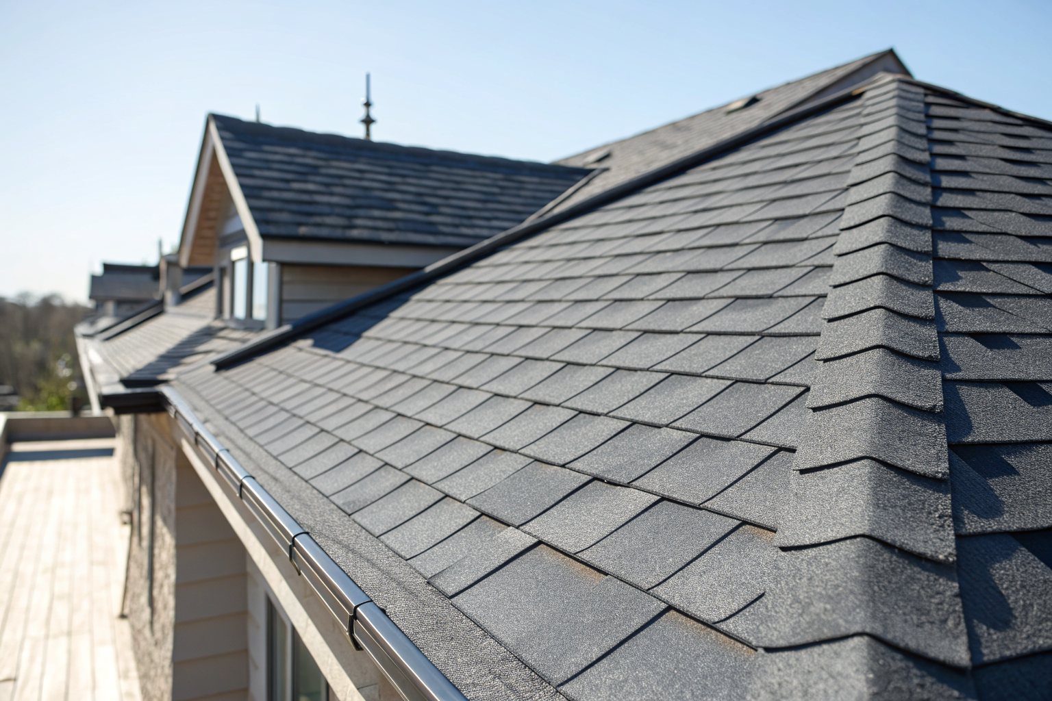 Close view of new charcoal-gray architectural shingles and a ridge cap in bright sun