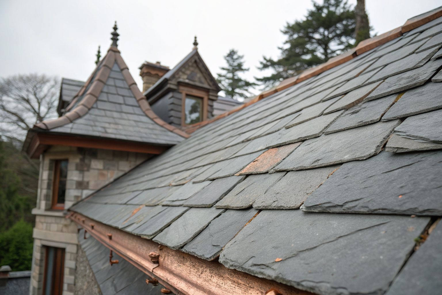 Close view of an old slate roof with cracked and slipped slates beside a copper valley and gutter